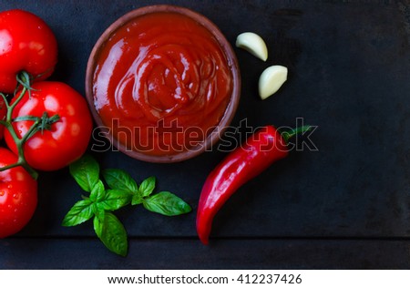 Tomato sauce salsa and ingredients - tomatoes, garlic, chili on dark stone background. Top view