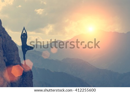 A woman practices yoga on a background of mountains and sky. Toned