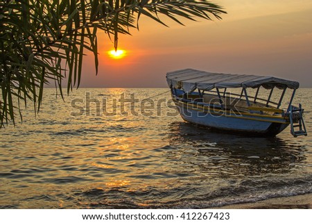 Beautiful view on moored boat on waves against of sunset at sea. Lake Victoria, Tanzania Royalty-Free Stock Photo #412267423
