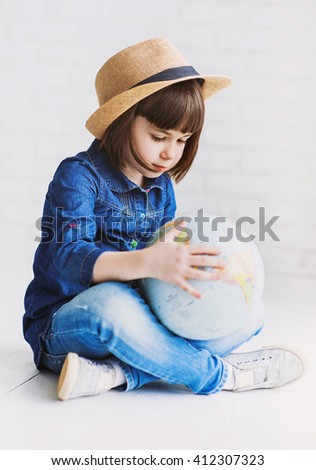 Little smiling girl holding globe, travel concept
