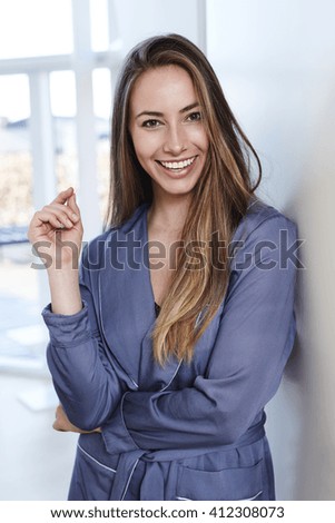 Smiling young woman in blue bathrobe