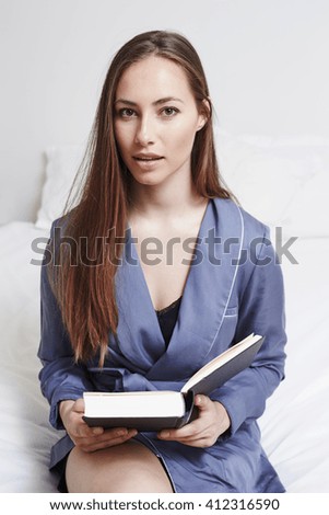 Portrait of beautiful woman with book in bedroom