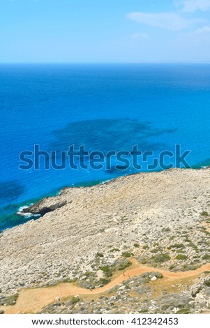 Man and women walking on the road located on a rocky coast of Mediterranean Sea on Cyprus island near Cape Greco National Park.