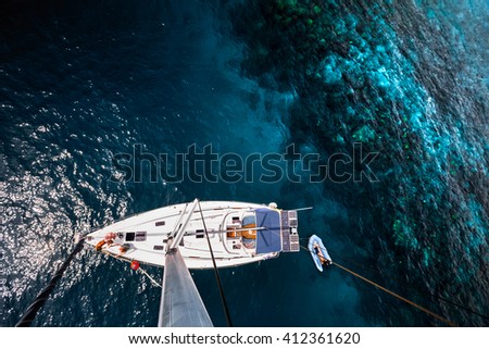Aerial shot of the sailing boat anchored near the coral tropical reef Royalty-Free Stock Photo #412361620