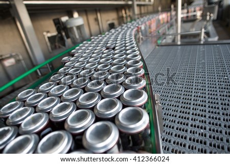 Stain-roof jars with drinks on the assembly line. for the production of alcoholic and soft drinks line. The final stage in the manufacture of the product. Royalty-Free Stock Photo #412366024