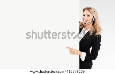 Portrait of support phone operator in headset showing blank signboard with copyspace area for text or slogan, on grey background