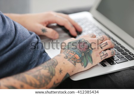 Young man with tattoo using laptop