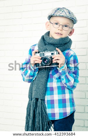 Little boy in a cap and scarf with retro camera, closeup