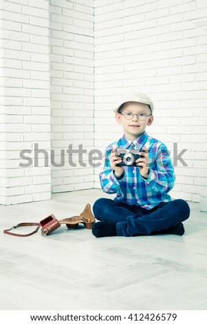 Little boy in a cap photographs. Sitting and photographs