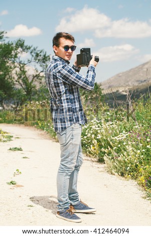 Man taking a picture with an old vintage camera in the countryside.