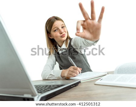 Happy smiling young girl showing okay gesture while using her laptop computer. Photo of teen school girl, creative concept with Back to school theme
