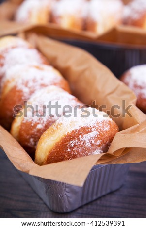 German donuts - berliner with jam and icing sugar in a box on a dark wooden table