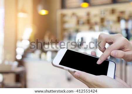Woman using touch screen mobile phone with Coffee shop blur background