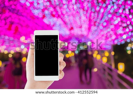 woman use mobile phone and blurred image of people on the bridge with beautiful pink light as the roof