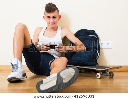 Happy young teenager burying in mobile phone and social networking indoors Royalty-Free Stock Photo #412596031