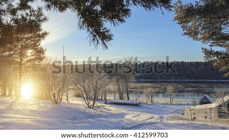 Winter landscape in Russian village during sunset. Snow, river in the background.