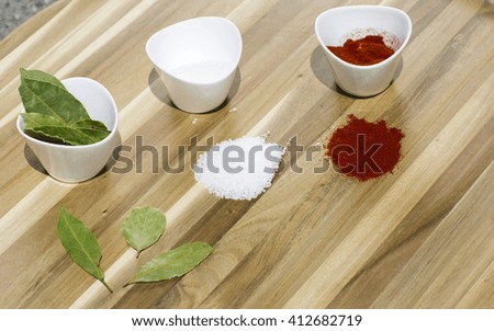Spices in small dishes on a tray. Salt, red pepper and Bay leaf on a wooden background.