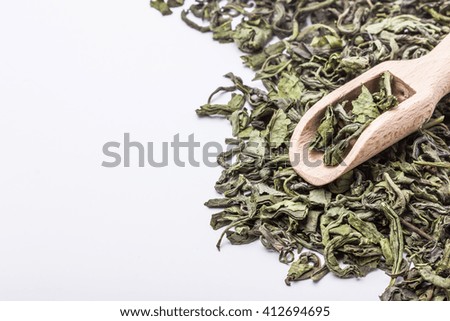 Natural green tea with wooden spoon isolated on white.