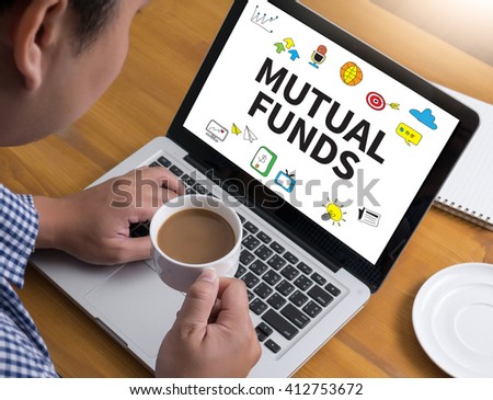 MUTUAL FUNDS Businessman at work. Close-up top view of man working on laptop while sitting at the wooden desk , coffee