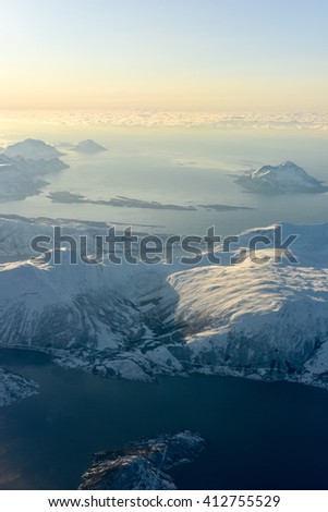 An aerial view of the snow covered mountains of the fjords of Norway in the winter.
