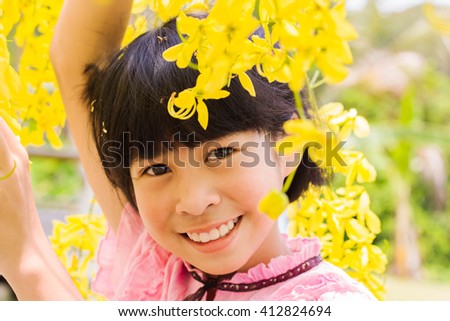 The image of a beautiful Asian girl smiling with yellow flowers in the fall.