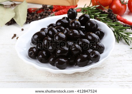 Black olives in the bowl with rosemary branch
