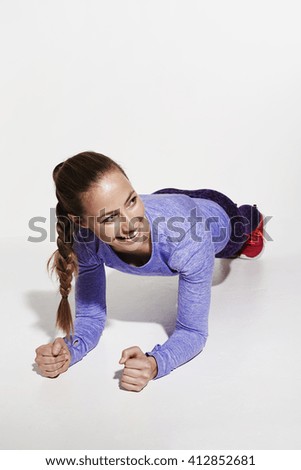 Beautiful athlete press ups in white studio, smiling