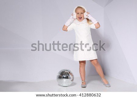 Little blonde girl with mirror sphere on white wall background