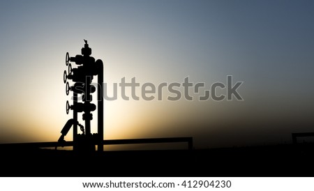Silhouette of wellhead in oilfield - sunset  