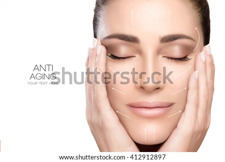 Anti aging treatment and plastic surgery concept. Beautiful young woman with hands on cheeks and eyes closed with a serene expression and white arrows over face. Isolated on white with copy space Royalty-Free Stock Photo #412912897