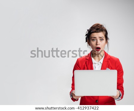 Surprised girl holding laptop over gray background