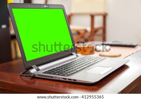 Laptop on wooden table in home, green screen - enhanced colors
