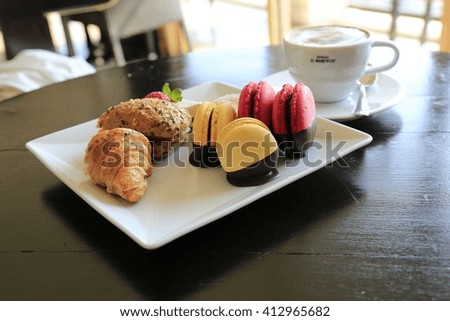 cup of cappuccino with croissant and macarons