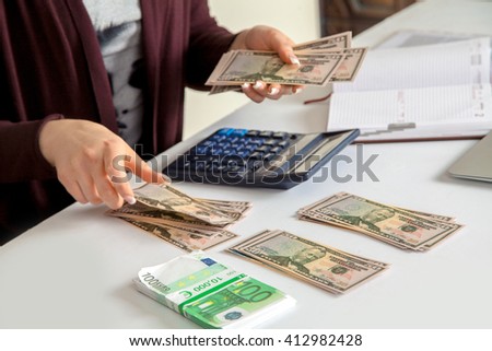 woman considers cash savings in the workplace. dollars and euro. Concept art of the financial crisis. horizontal photo