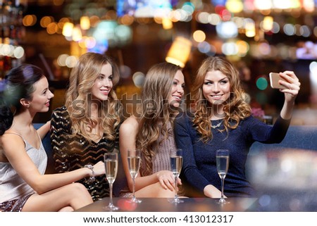 celebration, friends, bachelorette party, technology and holidays concept - happy women with champagne and smartphone taking selfie at night club