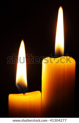 Two burning candles over a black background