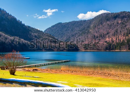 Wooden jetty at Alpsee lake with Alps mountains in the background. Bavaria, Germany.