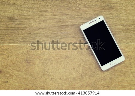 mobile phone on wood background.White smart phone with isolated screen on old wooden desk. phone on the table.mobile phone on a vintage hardwood desk and blank copy space.top view image of smartphone