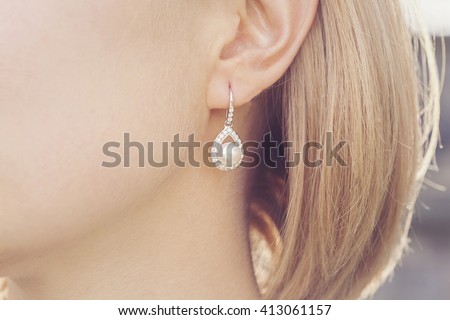 Detail of young woman wearing beautiful luxury earring  Royalty-Free Stock Photo #413061157