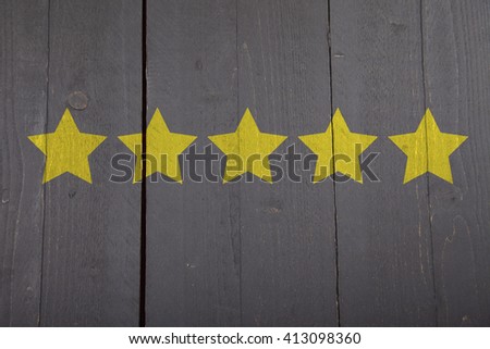 Five yellow ranking stars on black wooden background