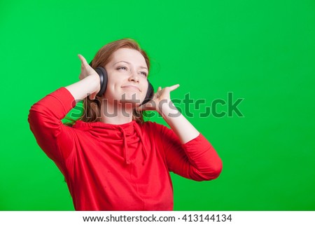 Woman listening music on headphones, green background
