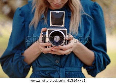 Girl in vintage blue dress holding old medium format camera.