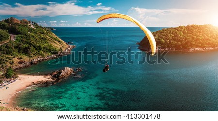 Skydiver flying over the water during sunset with the mountains Royalty-Free Stock Photo #413301478