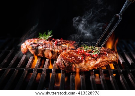 Beef steaks on the grill with flames Royalty-Free Stock Photo #413328976