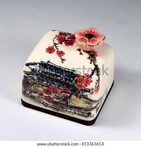 Toy music box. The ceramic case and a key flower. On the case picture cherry blossoms and Korean house.