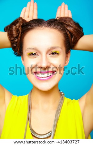 portrait of funny crazy fashion hipster girl  on blue background making rabbit ears 