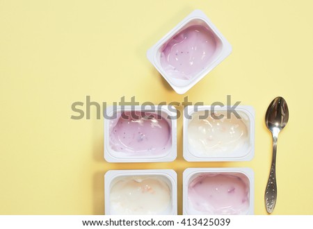 yogurt in plastic cups, on a yellow background.