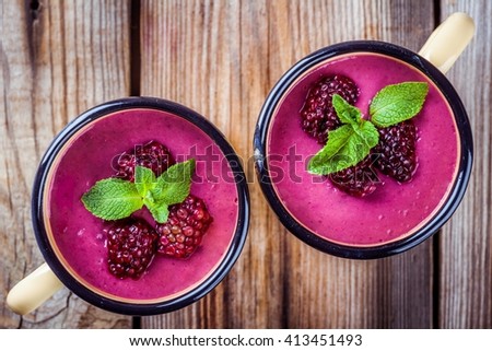 juicy blackberry smoothies in mugs on wooden table. above view