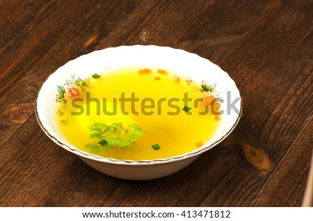 broth with vegetables in plate on wooden table .Rustic style.