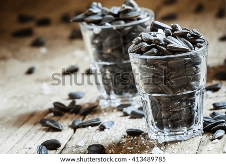 Salted sunflower seeds in a glass, vintage wooden background, selective focus